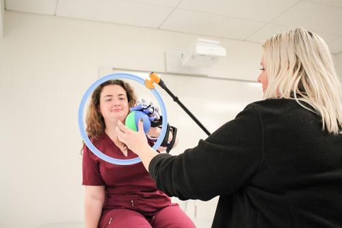 An OT student practices with hand mobility equipment.