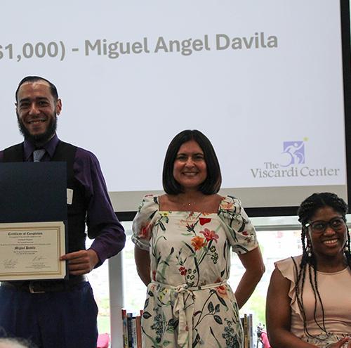 A Viscardi winner stands and poses with his certificate.
